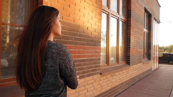 Молода жінка вигулює вулиці міста на заході сонця . — стокове відео