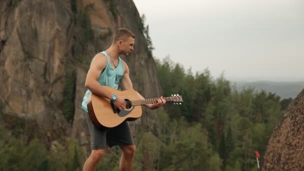 Человек, играющий на гитаре, стоя на вершине горы . — стоковое видео