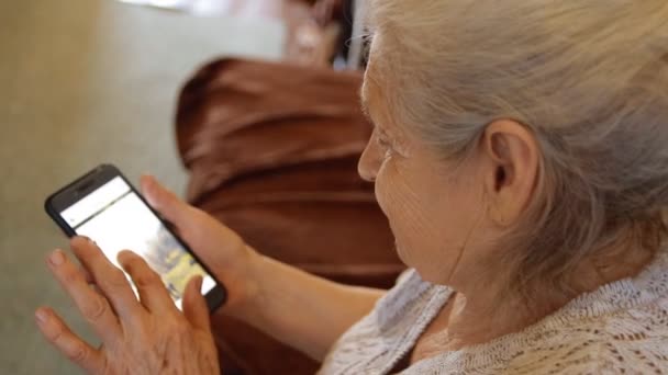 Close-up de uma mulher idosa usando um smartphone para ver as redes sociais . — Vídeo de Stock