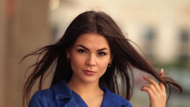 Portret stylowy młoda brunetka kobieta patrząc na kamery atrakcyjna kaukaski kobieta ubrana w niebieski płaszcz w miejskich miasta. — Wideo stockowe