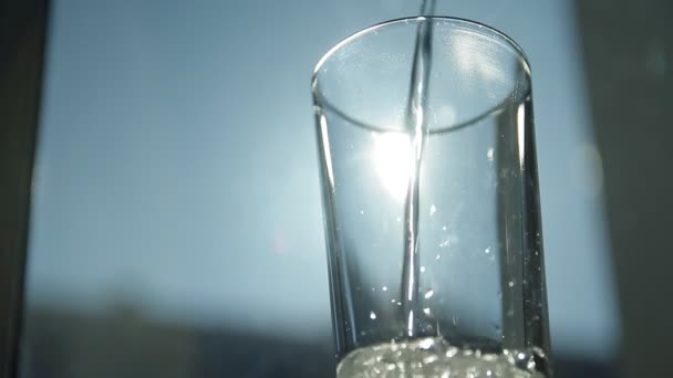 Primo piano estremo di acqua minerale frizzante versata in un bicchiere all'alba . — Video Stock
