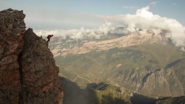 Brave man jumping off a cliff, rope jumping in the mountains. — Stock Video