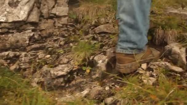 Fötterna på vandraren som går upp i backen och skjuta ned rock on leden. — Stockvideo