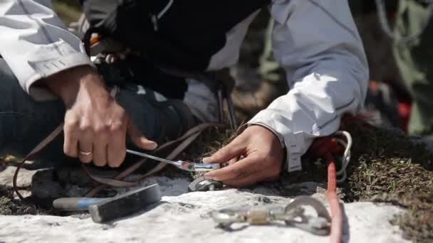 Close-up van de mans hand draaien de belangrijkste bout in de rots. Organisatie van de verzekering voor reddingswerk. — Stockvideo