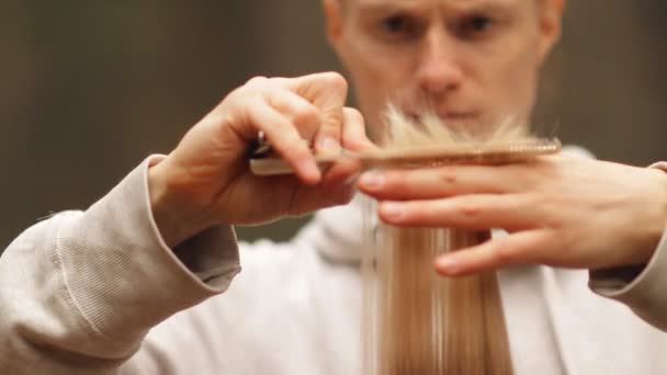 Young stylish male hairdresser doing hair cut for blonde woman outdoors. — Stock Video