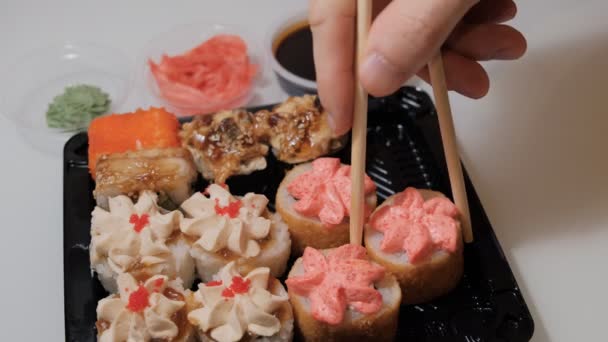 Hand takes the sushi roll with his chopsticks. — Stock Video