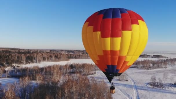 Aerial shot of the people fly on a big bright balloon over the winter forest. — Stock Video