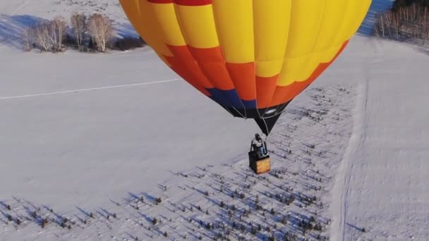 Antenn skott människor flyga på en stora ljusa ballong över vintern skogen. — Stockvideo