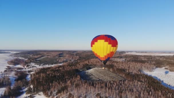 Légi felvétel az emberek egy nagy fényes léggömb átrepülnek a téli erdő. — Stock videók