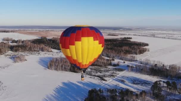 Antenn skott människor flyga på en stora ljusa ballong över vintern skogen. — Stockvideo