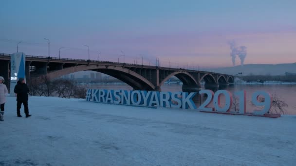 Красноярск, Россия - 20 января 2019 года: Символ зимней Универсиады 2019 года на фоне моста в Красноярске . — стоковое видео
