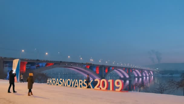 Krasnoyarsk, Rusland - 20 Jan, 2019: symbool van de winter Universiade 2019 op de achtergrond van de brug in Krasnojarsk. — Stockvideo