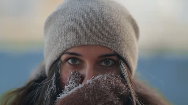 Porträtt av en ung charmig kvinna som täcker hennes ansikte med sin hand från kylan. — Stockvideo