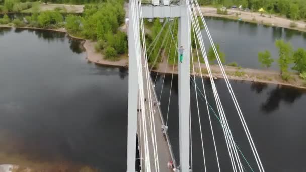 Ein Mann läuft auf einem Seil, das in großer Höhe zwischen den Stützen der Brücke gespannt ist. — Stockvideo