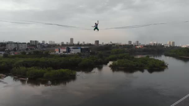 Krasnojarsk, Rosja-08 cze, 2019: człowiek idzie na liny rozciągnięty pomiędzy podporach mostu na dużej wysokości. — Wideo stockowe