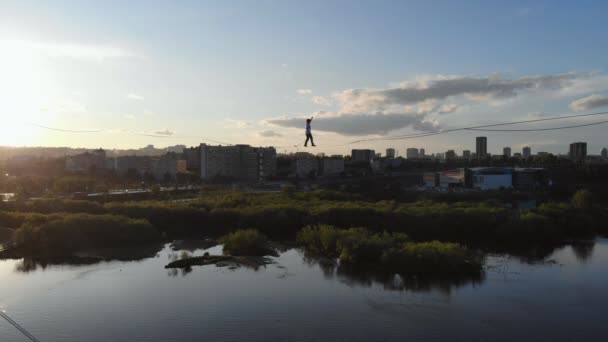 Красноярск, Россия - 08 июня 2019 г.: Мужчина идет по веревке, растянутой между опорами моста на большой высоте . — стоковое видео