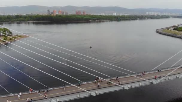 Krasnojarsk, Rusland-08 jun 2019: een man loopt op een touw gespannen tussen de steunen van de brug op grote hoogte. — Stockvideo