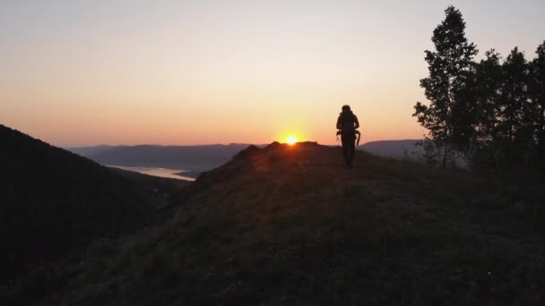 A túró sétál végig a hegyi ösvényen hordozó kis gyermeke a vállán a naplementekor. — Stock videók