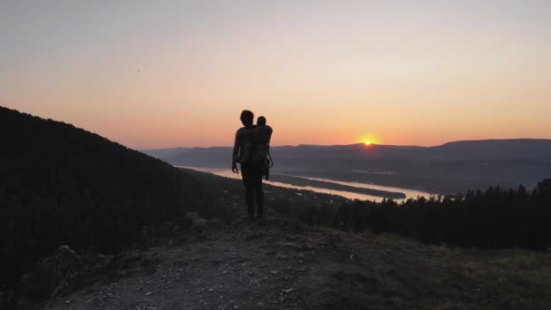 En man visar sitt barn solnedgången gå längs en bergsstig. — Stockvideo