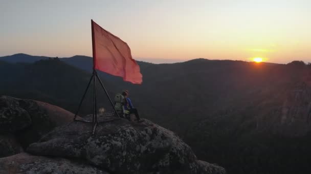 Luchtfoto van jonge reizigers vader en zijn twee-jarige zoon zitten op de top van een berg en kijken naar de zonsondergang. — Stockvideo