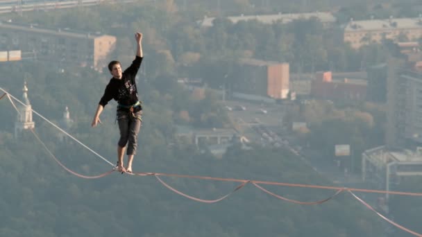 Moscú, Rusia - 8 Sep 2019: Un hombre equilibra en cuerda apretada, una vista de la ciudad desde la altura en la niebla . — Vídeos de Stock