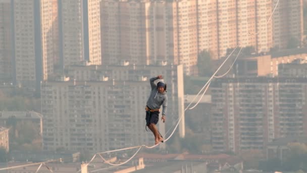 Moscou, Rússia - 8 de setembro de 2019: Um homem equilibra na corda apertada, uma visão da cidade da altura na névoa . — Vídeo de Stock