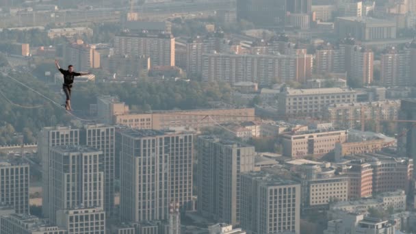 Moscú, Rusia - 8 Sep 2019: Un hombre equilibra en cuerda apretada, una vista de la ciudad desde la altura en la niebla . — Vídeos de Stock