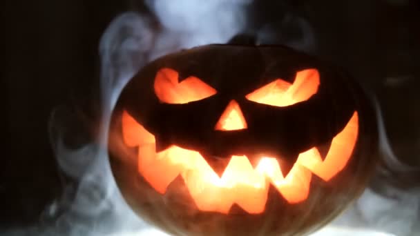 A brilhar Jack-O-Lanterna. Abóbora de Halloween com rosto assustador fumaça dentro com chama . — Vídeo de Stock