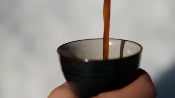 Mouvement lent du gros plan du café chaud versé dans une tasse .