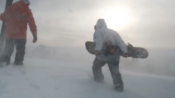 Sheregesh, Rússia - 07 de março de 2019: Movimento lento de um esquiador e snowboarder subindo ao topo de uma montanha ao amanhecer em uma tempestade . — Vídeo de Stock