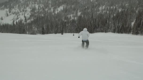 Een man is aan het snowboarden van een berg. — Stockvideo