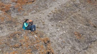 Bir kayanın üzerinde oturan ve küçük çocuğuyla oynayan mutlu bir annenin havadan görünüşü..