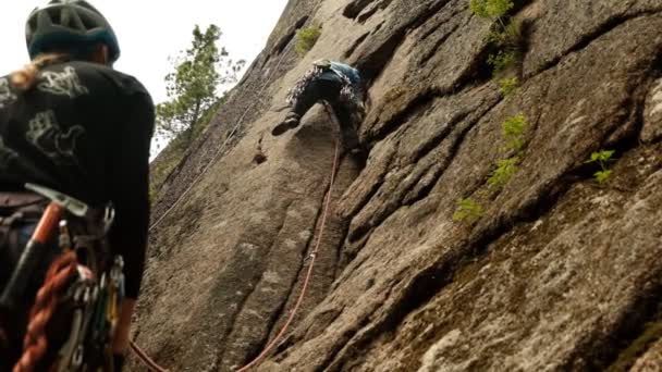 Krasnoyarsk, Rusia-15 de julio de 2019: Concursos de montañismo. Campeonato de Rusia en la clase de rock. Una mujer con una pareja sube a la cima de la montaña . — Vídeo de stock