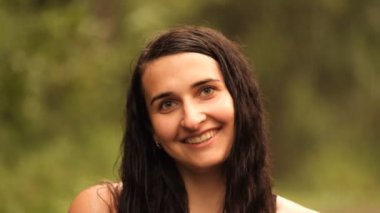 Yağmurda gülümseyen genç ve çekici bir kadının yavaş çekim portresi..