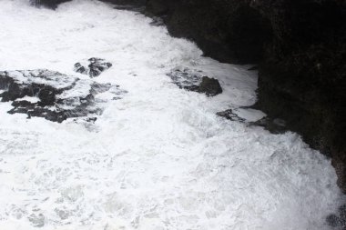 Dalgalar deniz köpüğü kayalar üzerine çökmesini