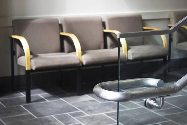 Row of chairs in waiting room with stairs handle in foreground