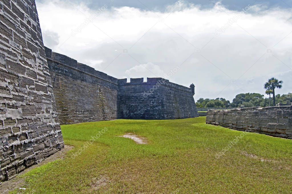 View of the Castillo de San Marcos fort, walls, towers, surrounding fields and palm trees. Saint Augustine, Florida, USA.
