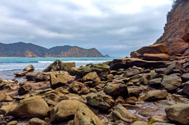 Arka planda okyanus ve gökyüzü olan her boyutta kayalar, bulutlu bir günde, Los Frailes Sahili Ulusal Parkı, Manabi, Ekvador