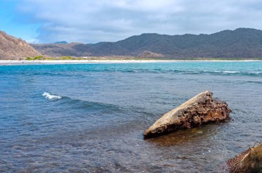 Okyanustaki kayalar sahile ve sahil dağlarına bakıyor. Los Frailes Sahili Ulusal Parkı, Ekvador.