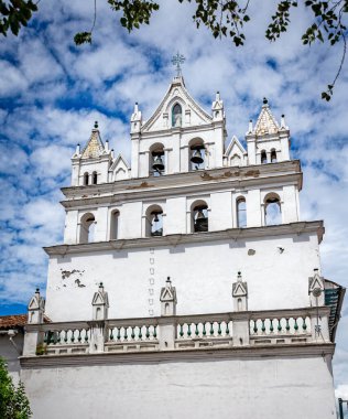 Cuenca, Ekvador 'daki eski kilise cephesi bulutlu ama güneşli bir sabahta kemer, çan ve sütunlarıyla. Koloni biçimi.