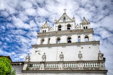 Cuenca, Ekvador 'daki eski kilise cephesi bulutlu ama güneşli bir sabahta kemer, çan ve sütunlarıyla. Koloni biçimi.