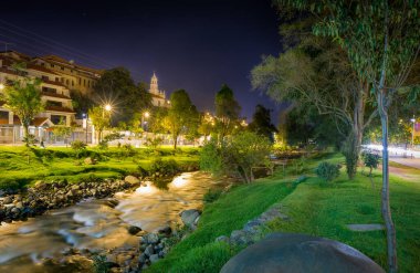 Tomebamba nehri gece Cuenca, Ekvador, Güney Amerika 'da popüler bir park ve yerleşim alanının yanında..