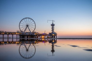 İçinde belgili tanımlık geçmiş ünlü Pier ile Hollanda Scheveningen Plajı, güzel gün batımı