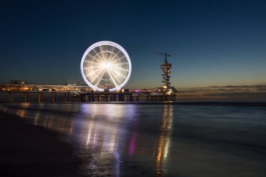 İçinde belgili tanımlık geçmiş ünlü Pier ile Hollanda Scheveningen Plajı, güzel gün batımı