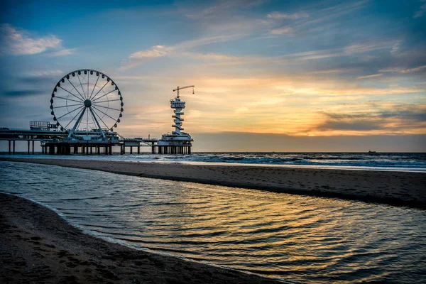 İçinde belgili tanımlık geçmiş ünlü Pier ile Hollanda Scheveningen Plajı, güzel gün batımı