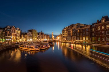 Hollanda, Amsterdam - Ağustos 2019: Amsterdam, Hollanda'nın Amstel nehri ile gece kenti görünümü