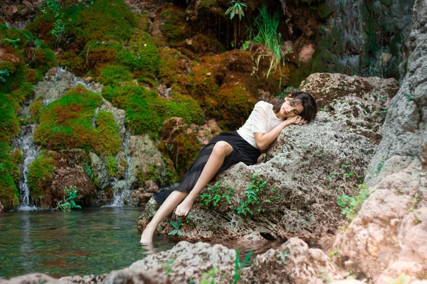 Hermosa chica morena posando en el río con plantas verdes. Sé Fotos De Stock Sin Royalties Gratis