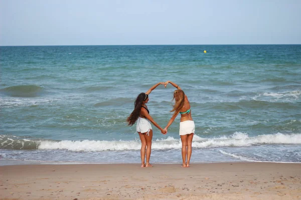 Zwei süße lustige junge Mädchen spazieren lachend am Strand entlang — Stockfoto