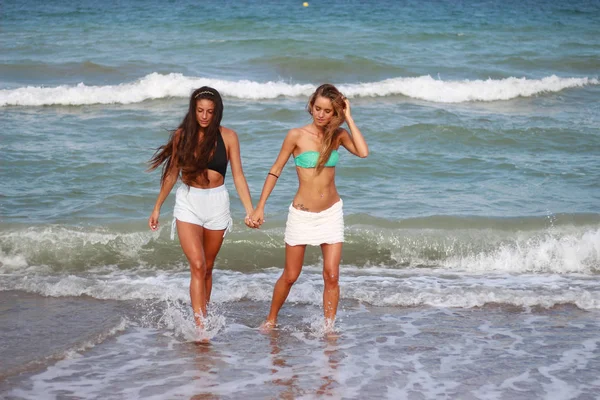 Dos chicas jóvenes divertidas lindas están caminando por la playa, riendo — Foto de Stock