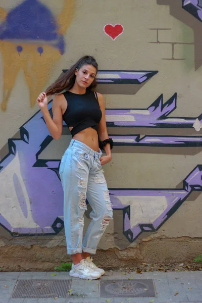 Moda hermosa modelo joven de pelo largo posando en el graffiti espalda —  Fotos de Stock